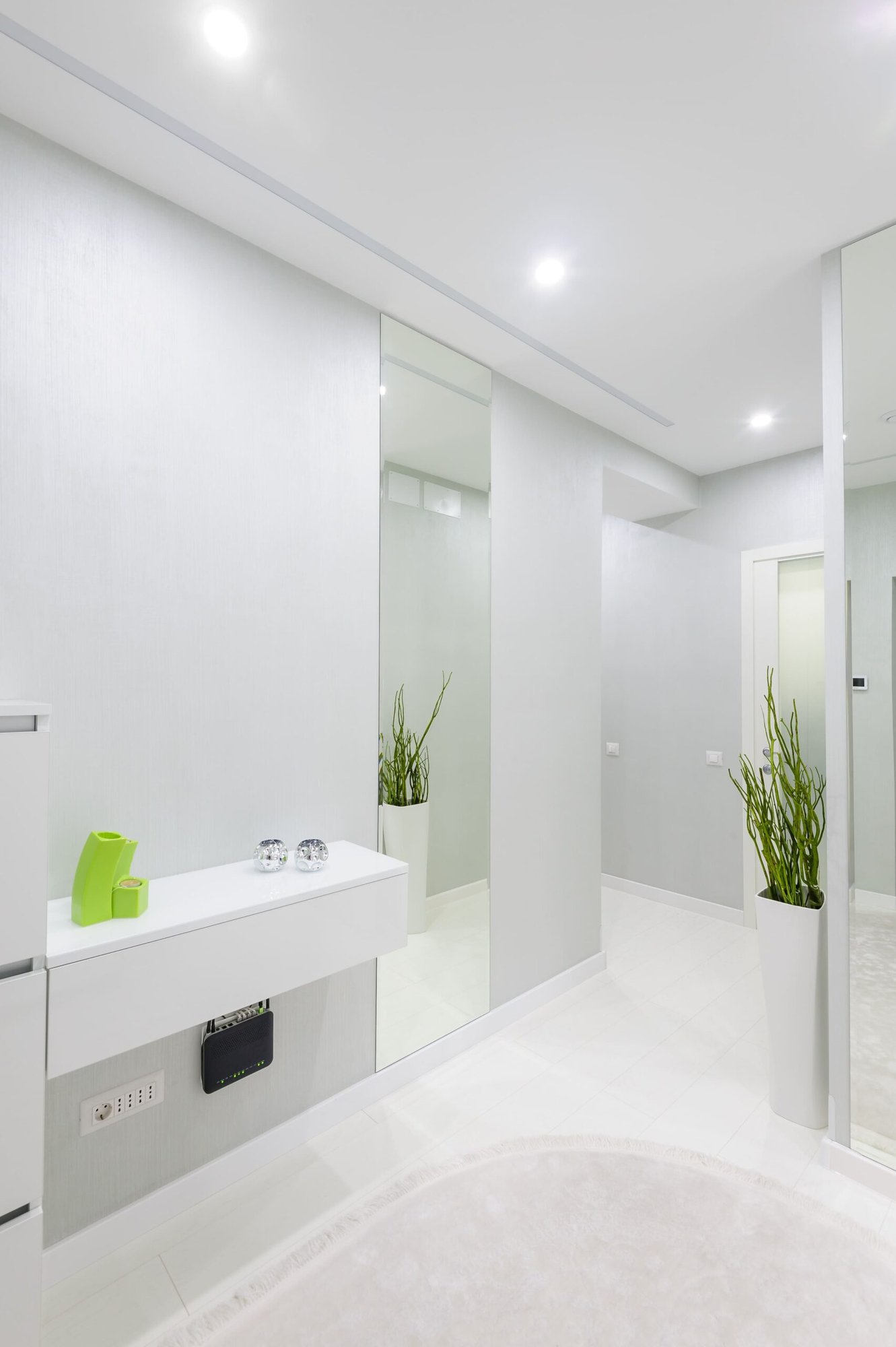 baño en tonalidades blancas, techos con iluminacion integrada y plantas